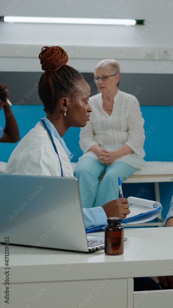 Fototapeta premium Doctor checking on elder patient healthcare in medical cabinet at treatment facility. Medic consulting old person for checkup appointment while sitting at desk. People talking at clinic