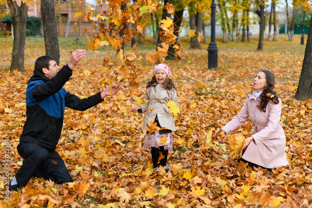 Portrait of a family in an autumn park. Happy people playing with fallen yellow leaves. Portrait of a family in an autumn park. Happy people playing with fallen yellow leaves.