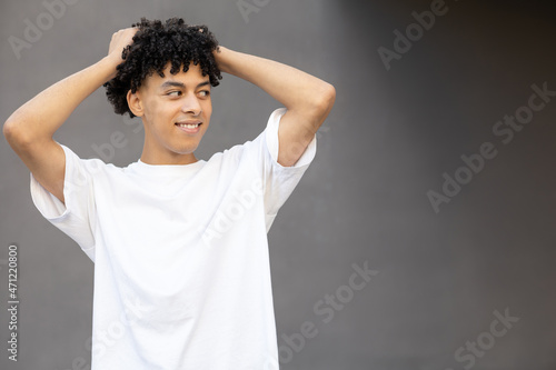 Gesture, emotion, expression and people concept - Mysterious American male holding himself by the hair, wearing a white T-shirt, looking at copy space on a dark gray background