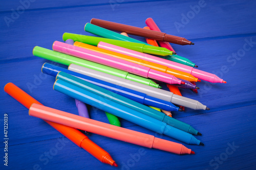 A set of different color markers on a blue background.