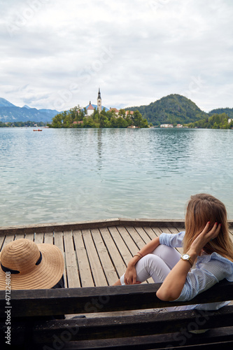 Young adult tourist woman sitting on a bench and enjoying on a lake. © astrosystem