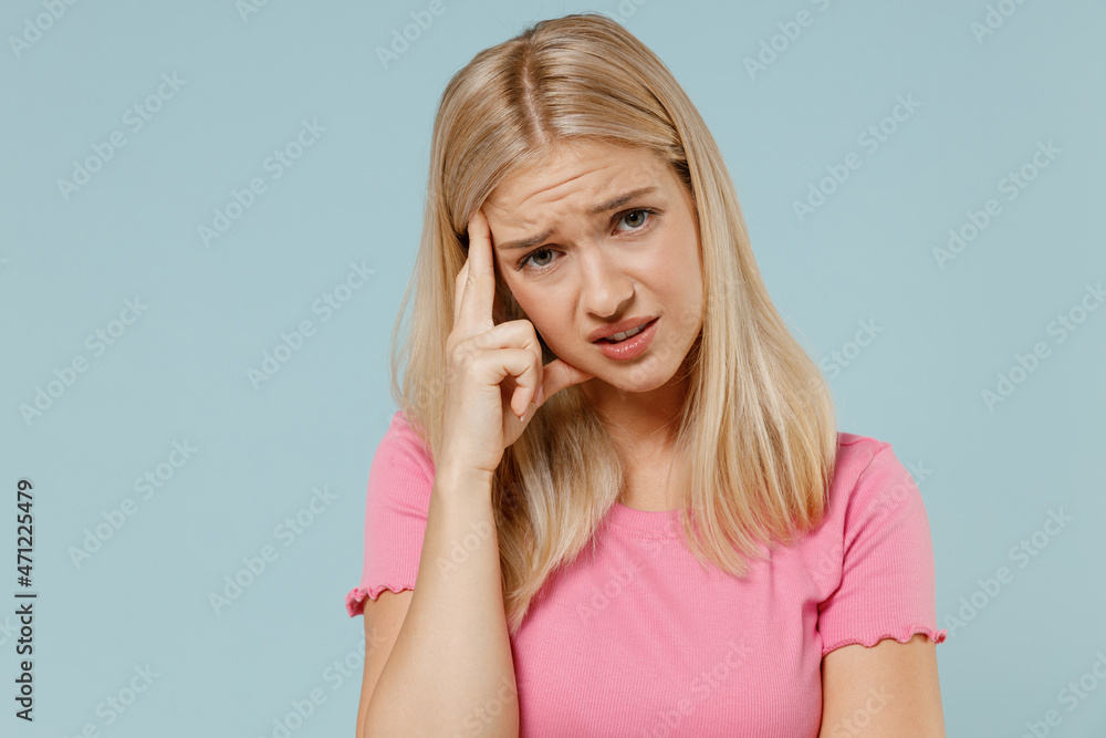 Young disappointed worried sad caucasian blonde woman 20s in casual pink t-shirt prop up forehead look camera isolated on plain pastel light blue background studio portrait. People lifestyle concept. Young disappointed worried sad caucasian blonde woman 20s in casual pink t-shirt prop up forehead look camera isolated on plain pastel light blue background studio portrait. People lifestyle concept.
