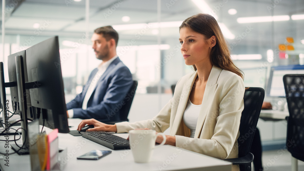 Young Confident Businesswoman Using Desktop Computer in Modern Office with Colleagues. Stylish Beautiful Manager Working on Commercial, Financial and Marketing Projects. Specialist in Diverse Team. Young Confident Businesswoman Using Desktop Computer in Modern Office with Colleagues. Stylish Beautiful Manager Working on Commercial, Financial and Marketing Projects. Specialist in Diverse Team.