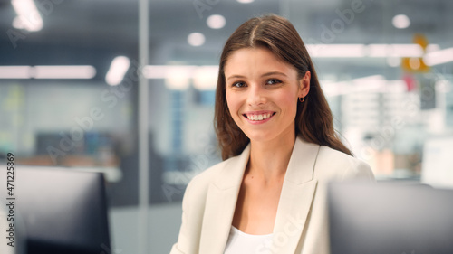 Portrait of a Beautiful Happy Young Female Wearing White Jacket, Looking at Camera, Posing and Charmingly Smiling. Successful Brunette Woman with Brown Eyes Working in Diverse Company Office.