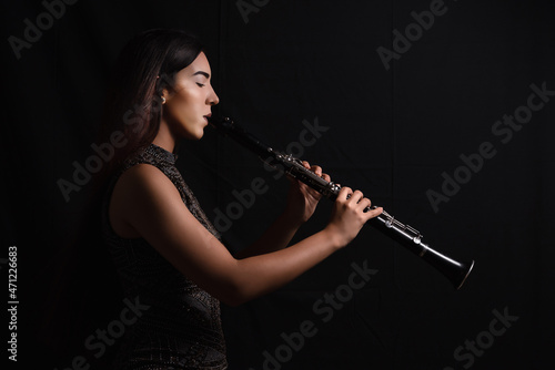 Billede på lærred Side View Of A Young Woman Playing Clarinet