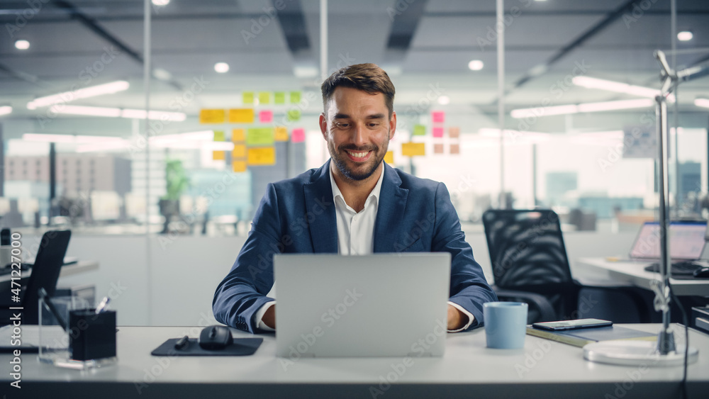 Busy Young Businessman Using Laptop Computer in Modern Office. Manager Thinks About Successful Financial Ideas. Happy Man Smiling About Finding Problem Solving Solutions for Company. Busy Young Businessman Using Laptop Computer in Modern Office. Manager Thinks About Successful Financial Ideas. Happy Man Smiling About Finding Problem Solving Solutions for Company.