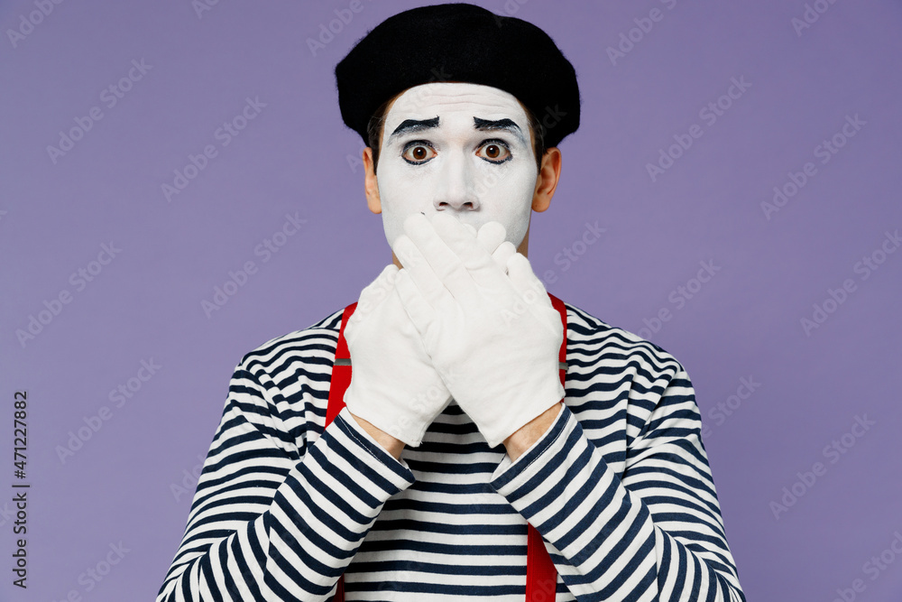 Secret strict silence young mime man with white face mask wears striped shirt beret covering mouth with hands do not want to speak isolated on plain pastel light violet background studio portrait.
