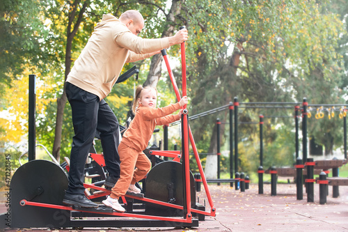 A man with his child, his little daughter, performs exercises on the sports ground of the city, the concept of an active healthy lifestyle in the family. teaching children exercises and training