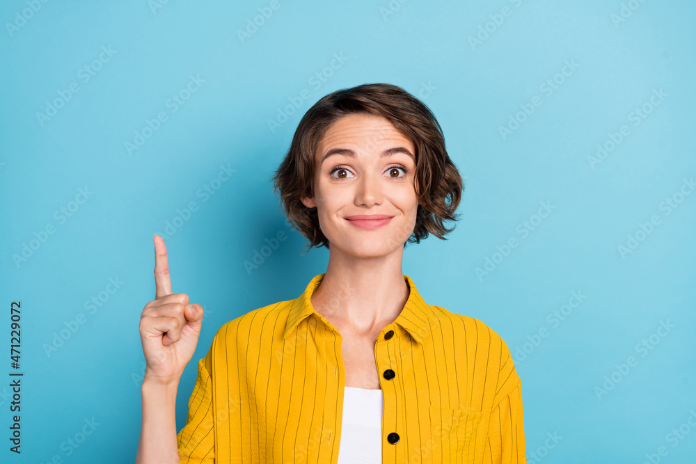 Photo of excited lady direct forefinger up empty space novelty wear yellow shirt isolated blue color background Photo of excited lady direct forefinger up empty space novelty wear yellow shirt isolated blue color background