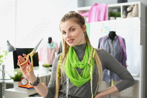 Female successful designer posing with scissors and tape measure on neck