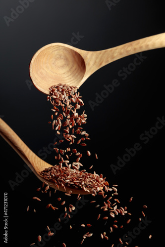 Foto Grains of flaxseed are poured with wooden spoons.
