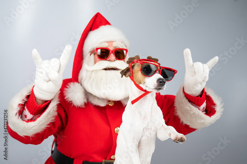 Santa claus and santa's helper in sunglasses on a white background. Jack russell terrier dog in a deer costume © Михаил Решетников