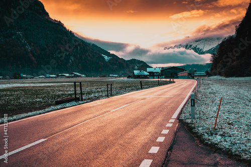 road at sunset leading to snow covered mountain peaks