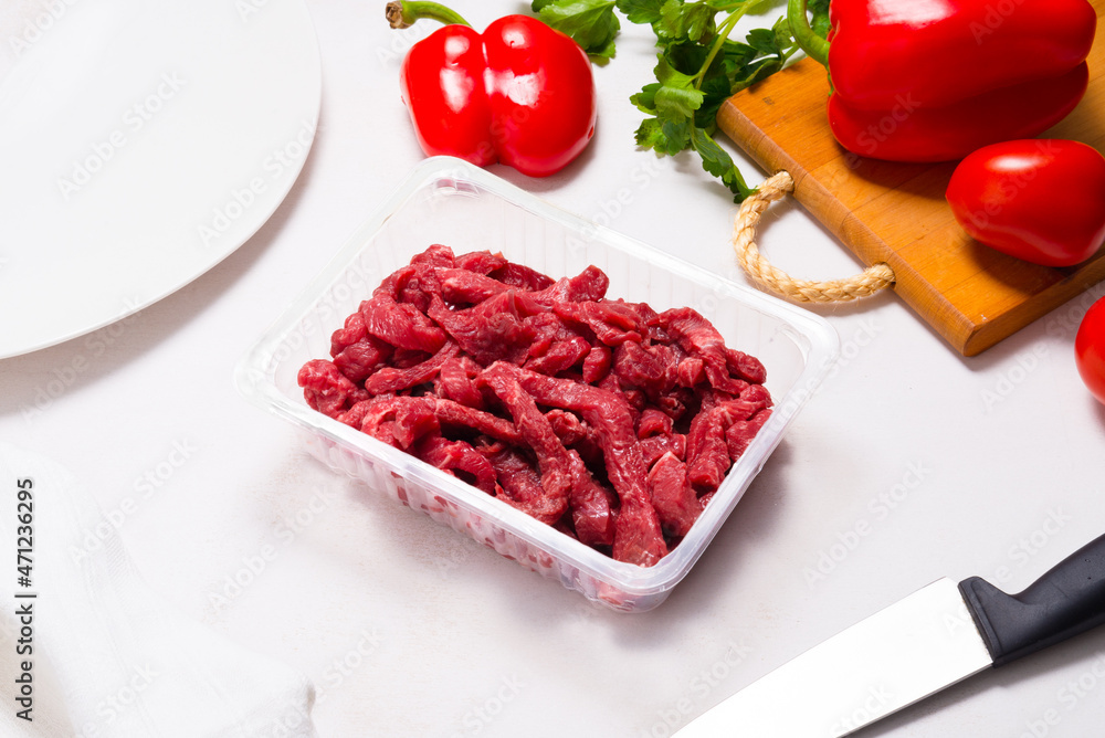 Raw beef stroganoff in plastic container on kitchen table Raw beef stroganoff in plastic container on kitchen table