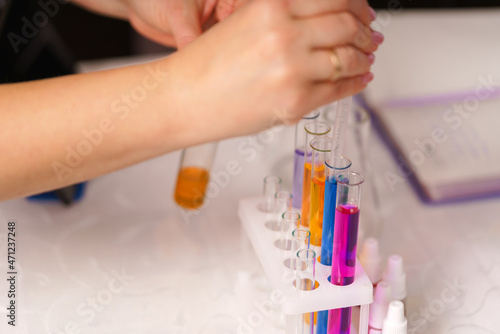 white female hands of a laboratory assistant pour chemical reagents. A woman works in a laboratory. Chemical elements in test tubes.