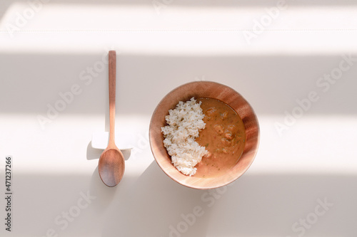 Curry over rice in a wooden bowl.