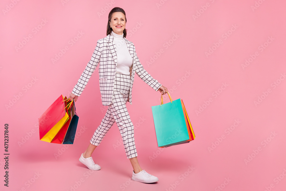 Full size photo of cheerful beautiful grandmother go shopping crazy shopaholic isolated on pink color background