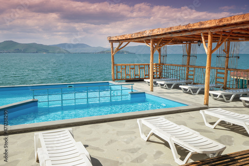 Sun loungers and sunbeds near the swimming pool with view on Lake Sevan in Armenia. Rest and vacation concept