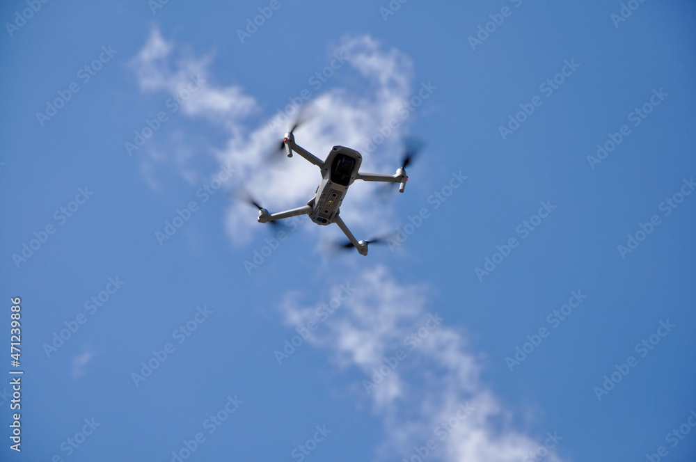 White Drone Flying on Nature Background. Drone Hanging in Air Flying Helicopter Dron Remote Control Air Drone White Drone Flying on Nature Background. Drone Hanging in Air Flying Helicopter Dron Remote Control Air Drone