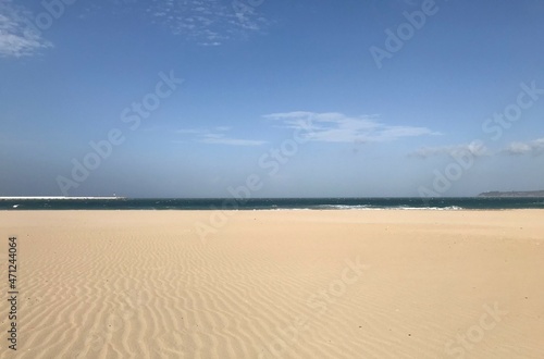 Large golden sandy beach and blue sky with sea in horizon. Empty large sandy beach.