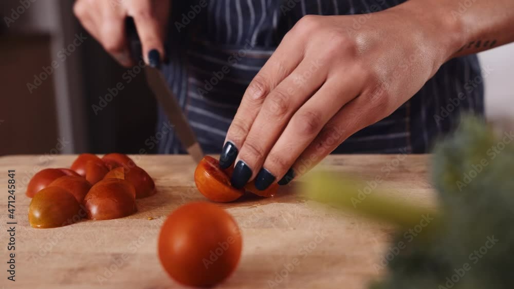 Multi-cultural young female chopping up tomatoes on wooden chopping board in kitchen. Fresh and healthy lifestyle Multi-cultural young female chopping up tomatoes on wooden chopping board in kitchen. Fresh and healthy lifestyle