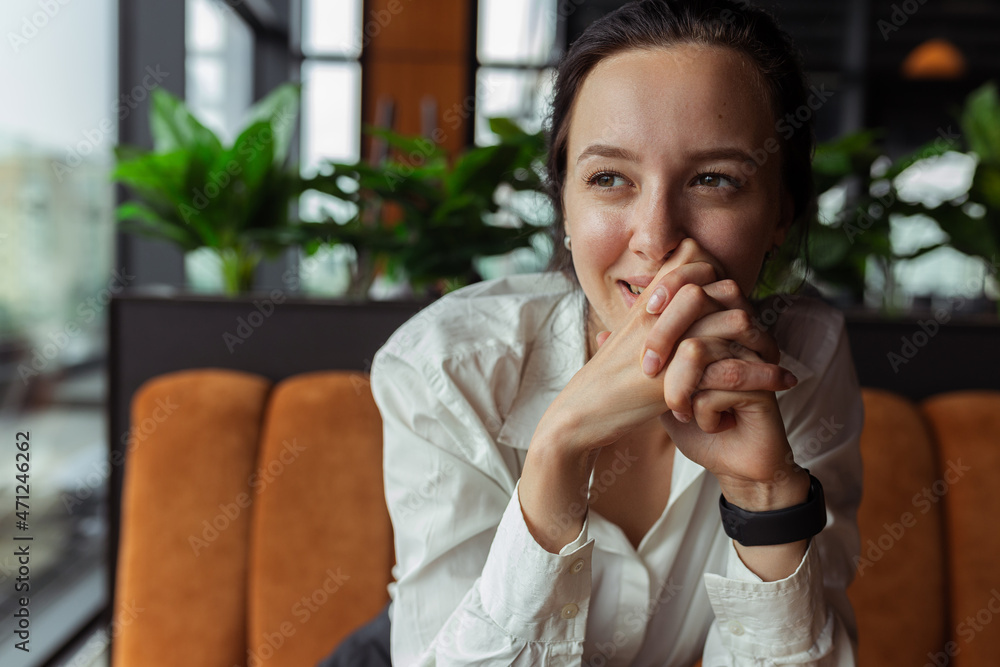 Happy businesswoman in white shirt leaning on hands and looking away with smile while sitting at table and working in cafe Happy businesswoman in white shirt leaning on hands and looking away with smile while sitting at table and working in cafe