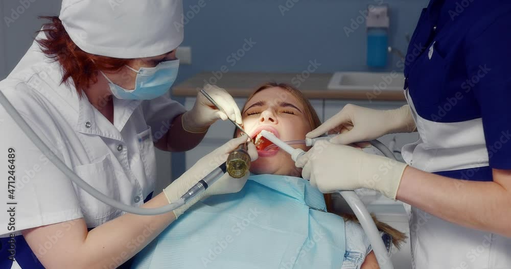 Dentist a woman in a medical uniform applies a retractor to a Caucasian ...