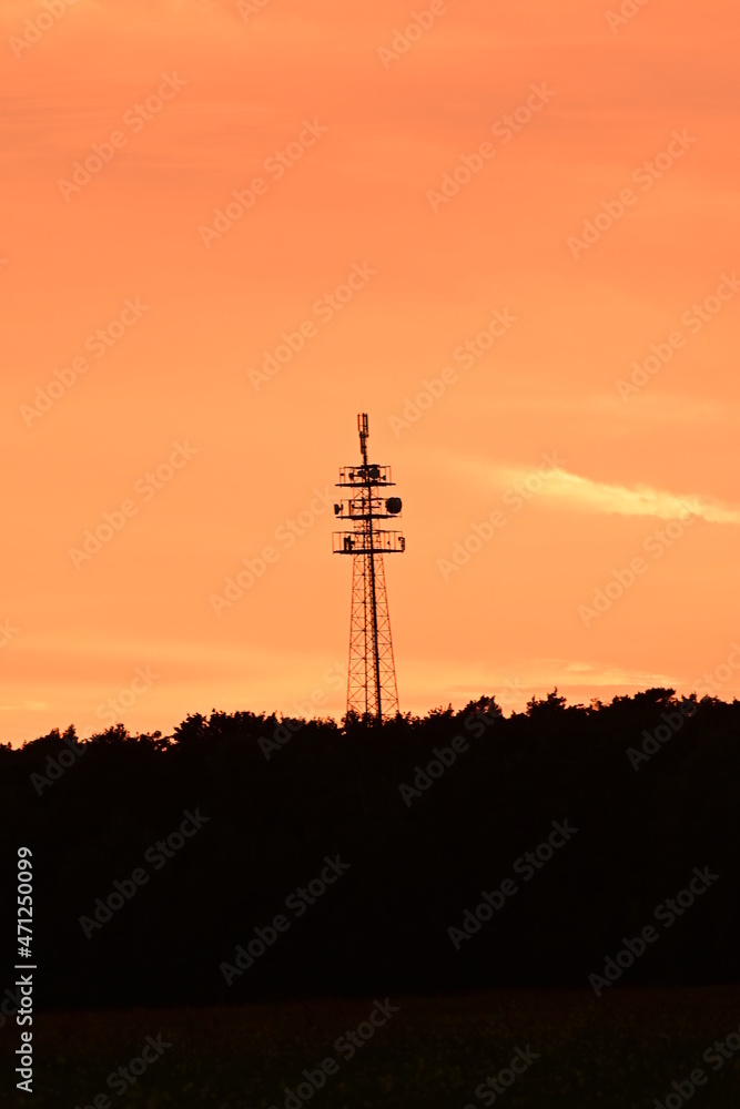 Fototapeta premium Silhouette eine Funkmastes mit Wald im Sonnenuntergang