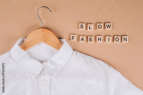 Slow fashion concept. White shirt on hangers on beige background. Conscious and environmentally friendly consupmtion - new modern trends in shopping. Zero waste, selective focus. Mockup image photo