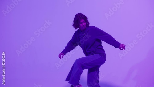 Woman dancing hip hop on colour changing neon background in studio. Modern choreography, dvertising of dance school, dancer expressing feelings for music video performance. photo