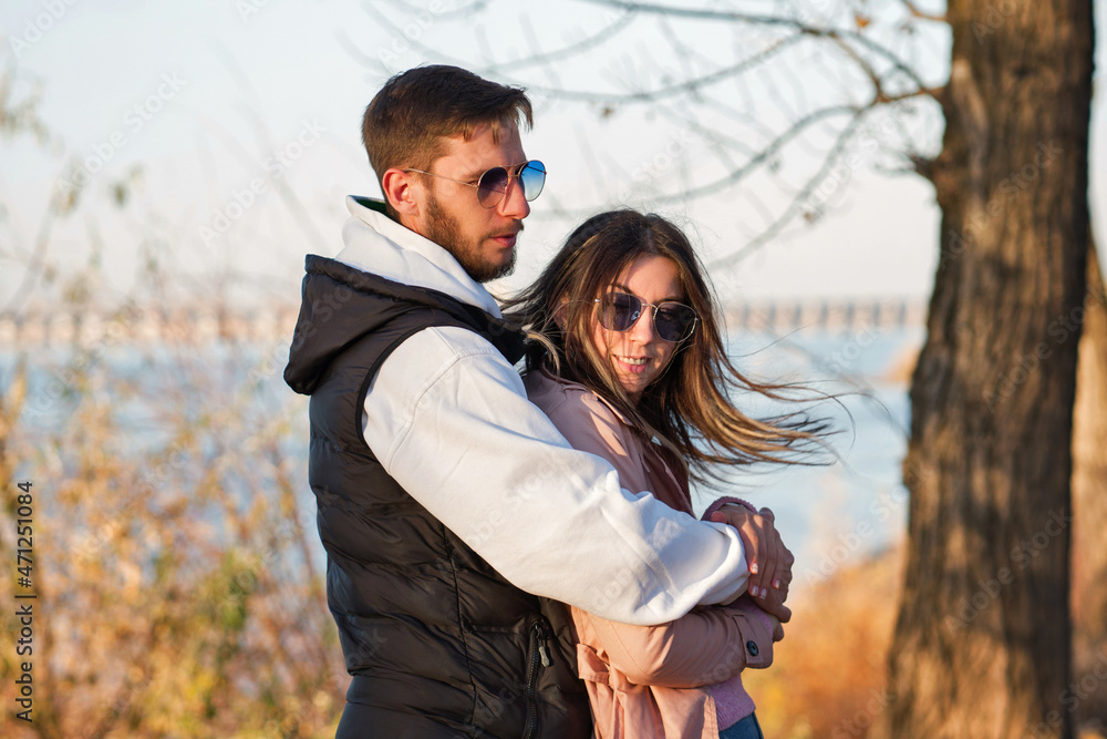 Outdoor shot young loving couple walking. Lovers posing in autumn leaves forest background. Concept of youth, love and lifestyle. Authentic real people portrait. Candid portrait. Outdoor shot young loving couple walking. Lovers posing in autumn leaves forest background. Concept of youth, love and lifestyle. Authentic real people portrait. Candid portrait.