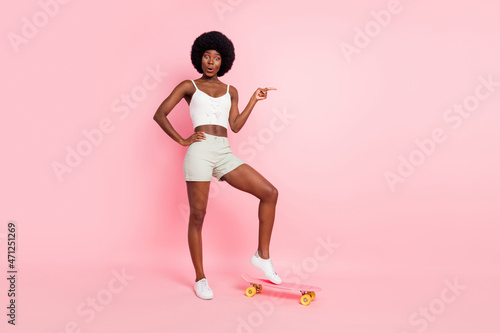 Photo of crazy lady skateboarding direct finger empty space wear cropped top shorts shoes isolated pink color background