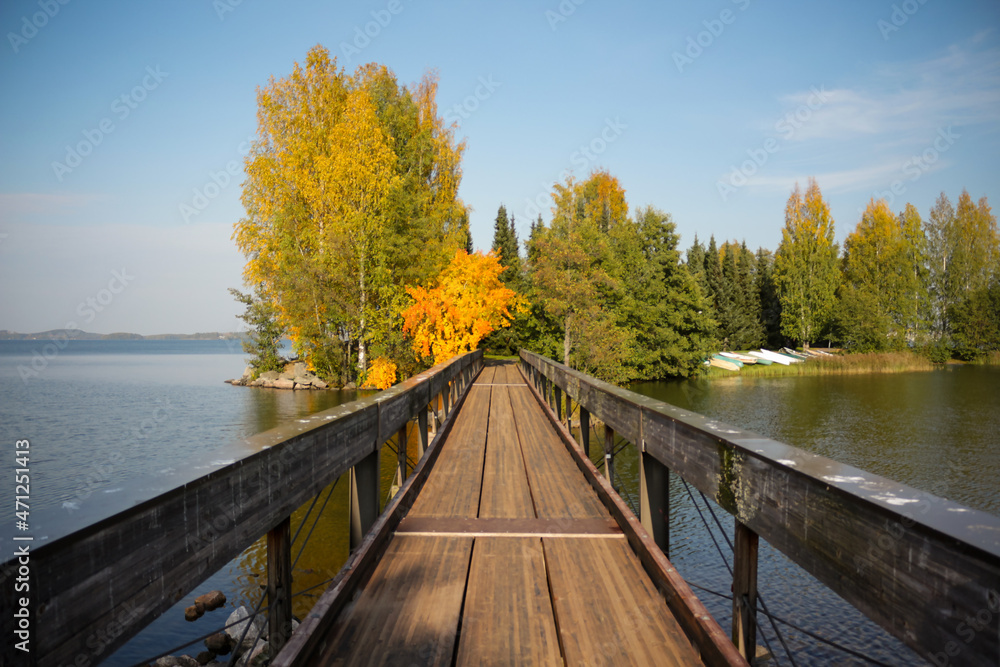A wooden bridge leading to a small island. Colorful autumn landscape