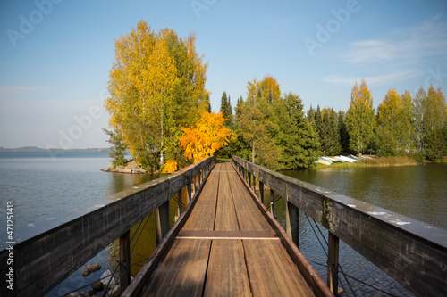 A wooden bridge leading to a small island. Colorful autumn landscape