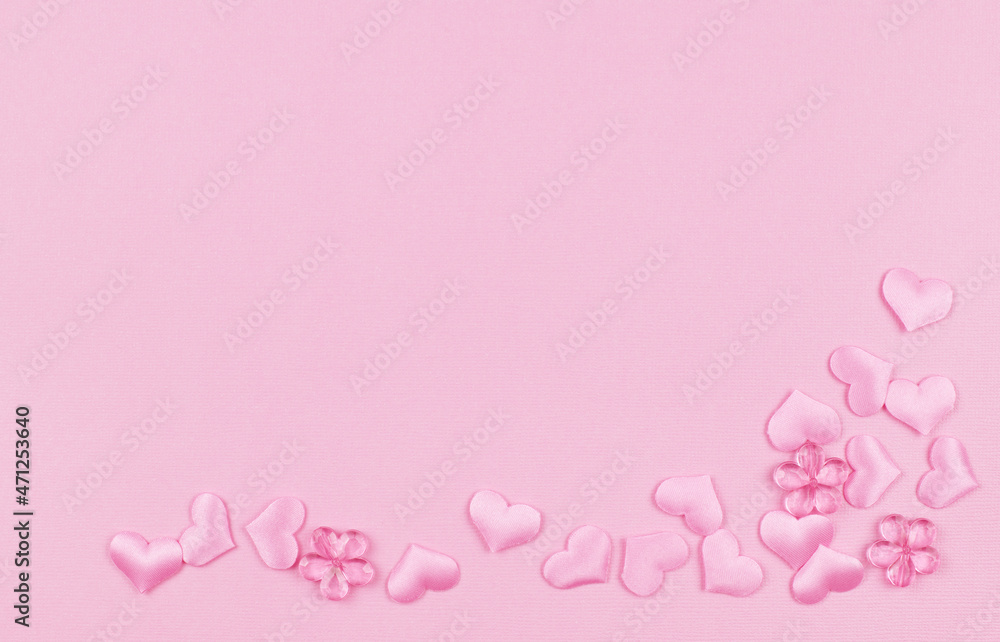 Pink satin hearts in a corner arrangement on paper texture for Valentine Day