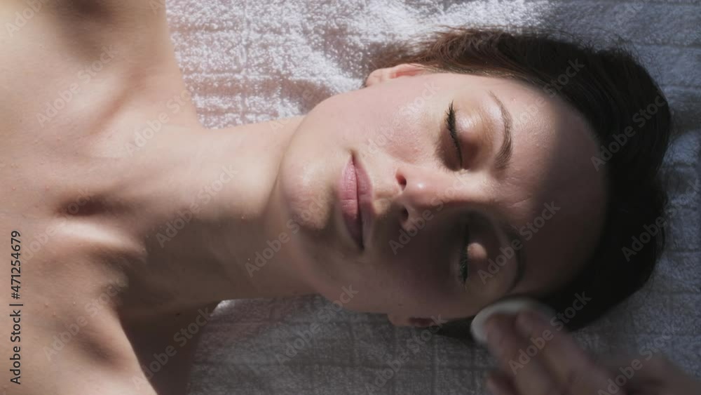 Beautician cleaning female face with cotton pad or sponge Beautician cleaning female face with cotton pad or sponge