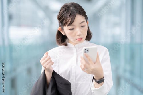 不安な表情でスマートフォンを見る女性