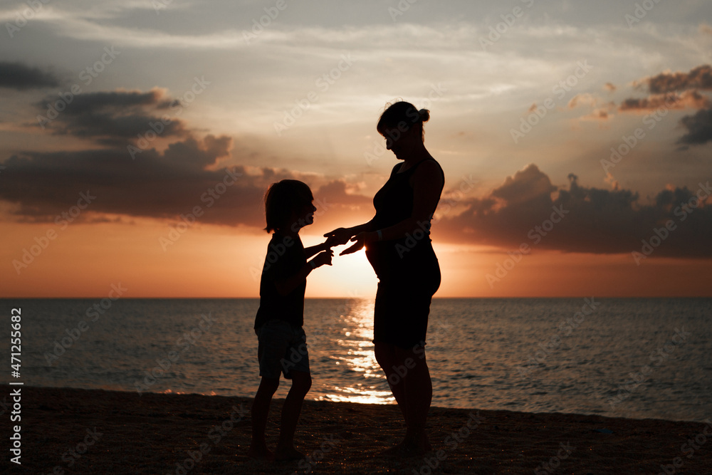 family on the beach. Silhouettes of people against the sunset. 2 people holding hands