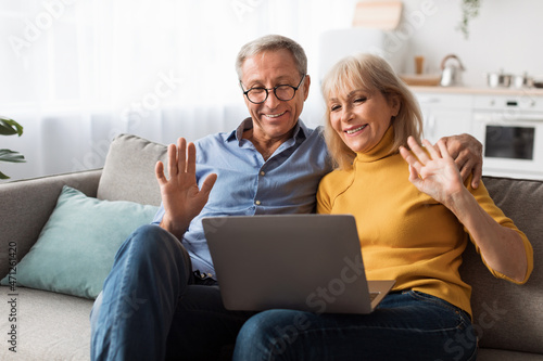 Mature Spouses Video Calling Waving Hello To Laptop At Home