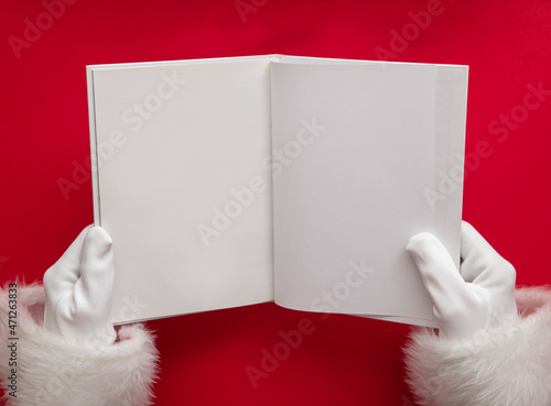 Santa claus holding a book with blank pages. Christmas book mockup photo