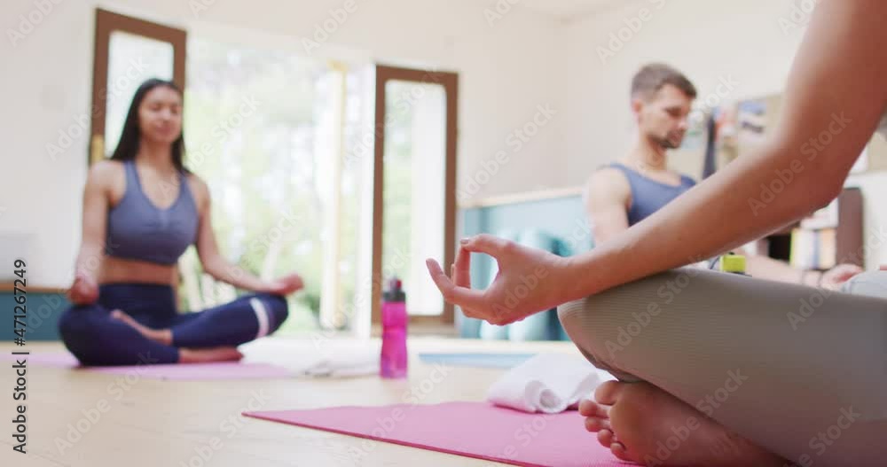 Caucasian female instructor, diverse man and woman sitting in lotus position on mats at yoga class Caucasian female instructor, diverse man and woman sitting in lotus position on mats at yoga class