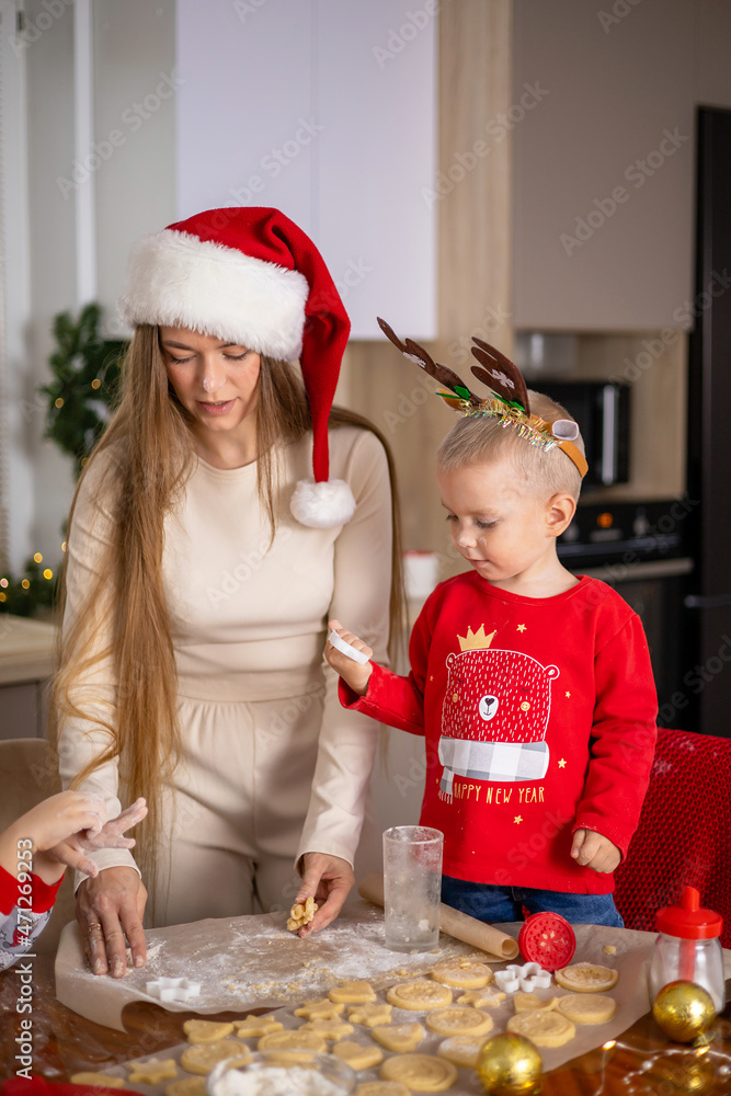 Merry Christmas. Happy Mom with children son bake Christmas cookies. Kitchen at home. Festive atmosphere Merry Christmas. Happy Mom with children son bake Christmas cookies. Kitchen at home. Festive atmosphere