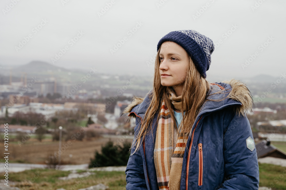 Beautiful young woman in blue coat, scarf and hat. Wet hair at rainy day in Norway. City in background. Beautiful young woman in blue coat, scarf and hat. Wet hair at rainy day in Norway. City in background.