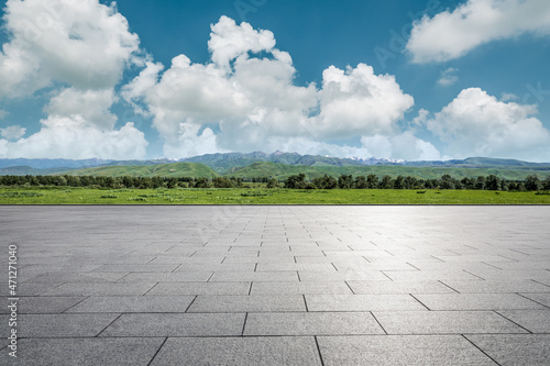 Empty square floor and green mountains under blue sky