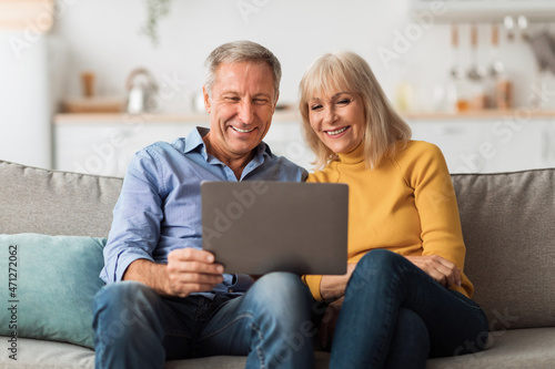 Happy Mature Couple Using Laptop Browsing Internet Together At Home