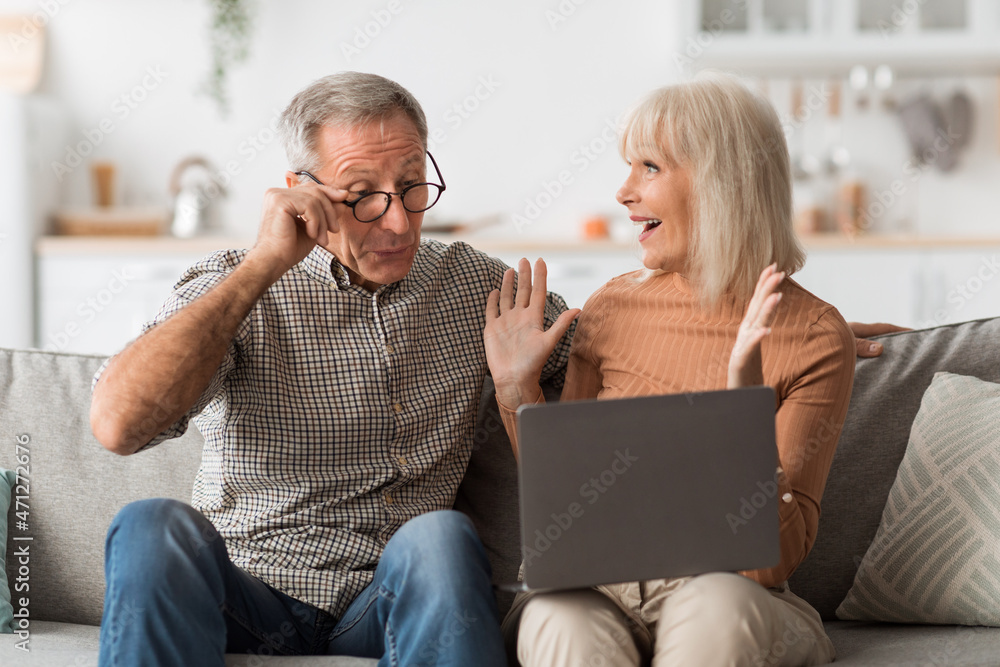 Joyful Senior Spouses Looking At Laptop Celebrating Success At Home