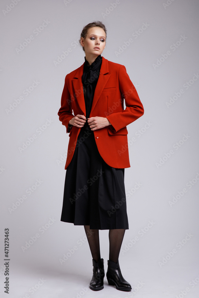 Fashion photo of a beautiful elegant young woman in a pretty suit, red jacket, black transparent blouse, short pants posing over white, soft gray background. Studio Shot. Full Fashion photo of a beautiful elegant young woman in a pretty suit, red jacket, black transparent blouse, short pants posing over white, soft gray background. Studio Shot. Full