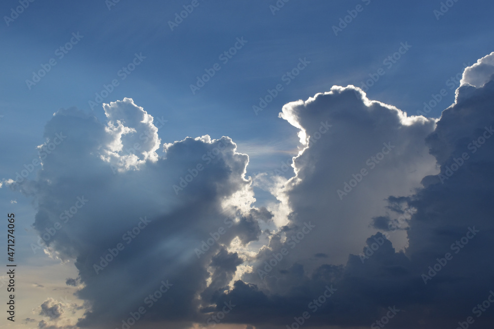 sunlight shining through clouds. blue sky with white cloud. In sunny summer, huge clouds float on the blue sky. sunlight shining through clouds. blue sky with white cloud. In sunny summer, huge clouds float on the blue sky.