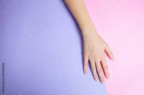 a beautiful female hand lowered to a pink and lilac background 