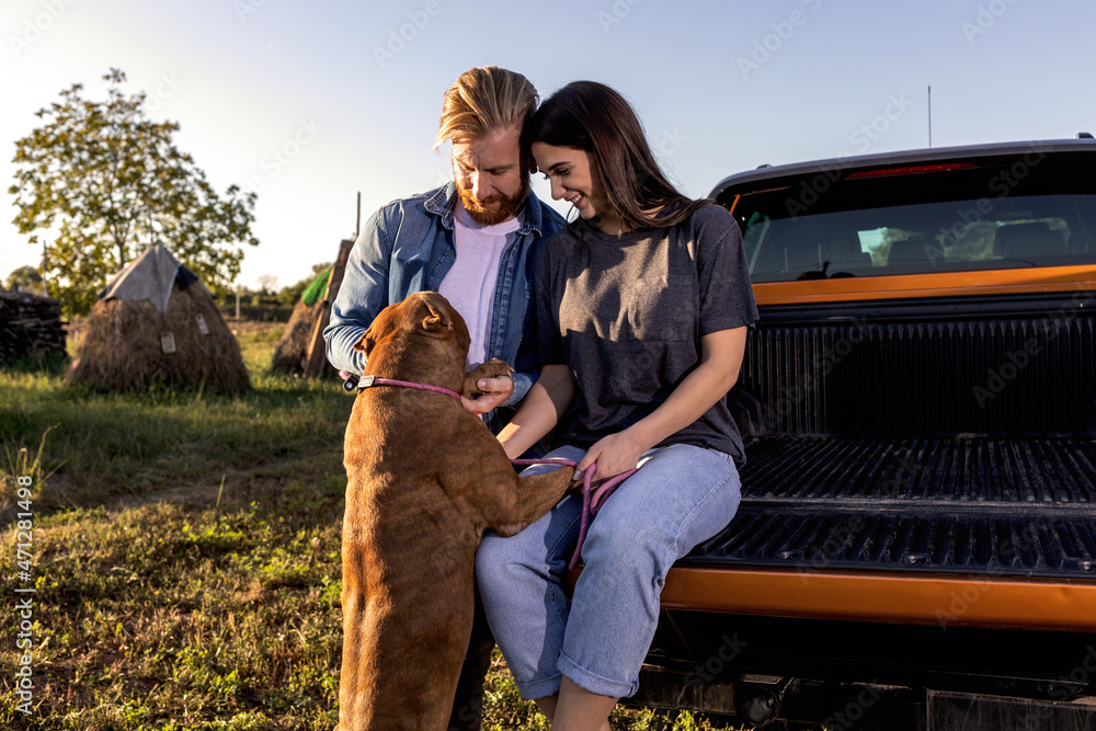 Loving couple spending time together with their canine bully dog friend in the countryside